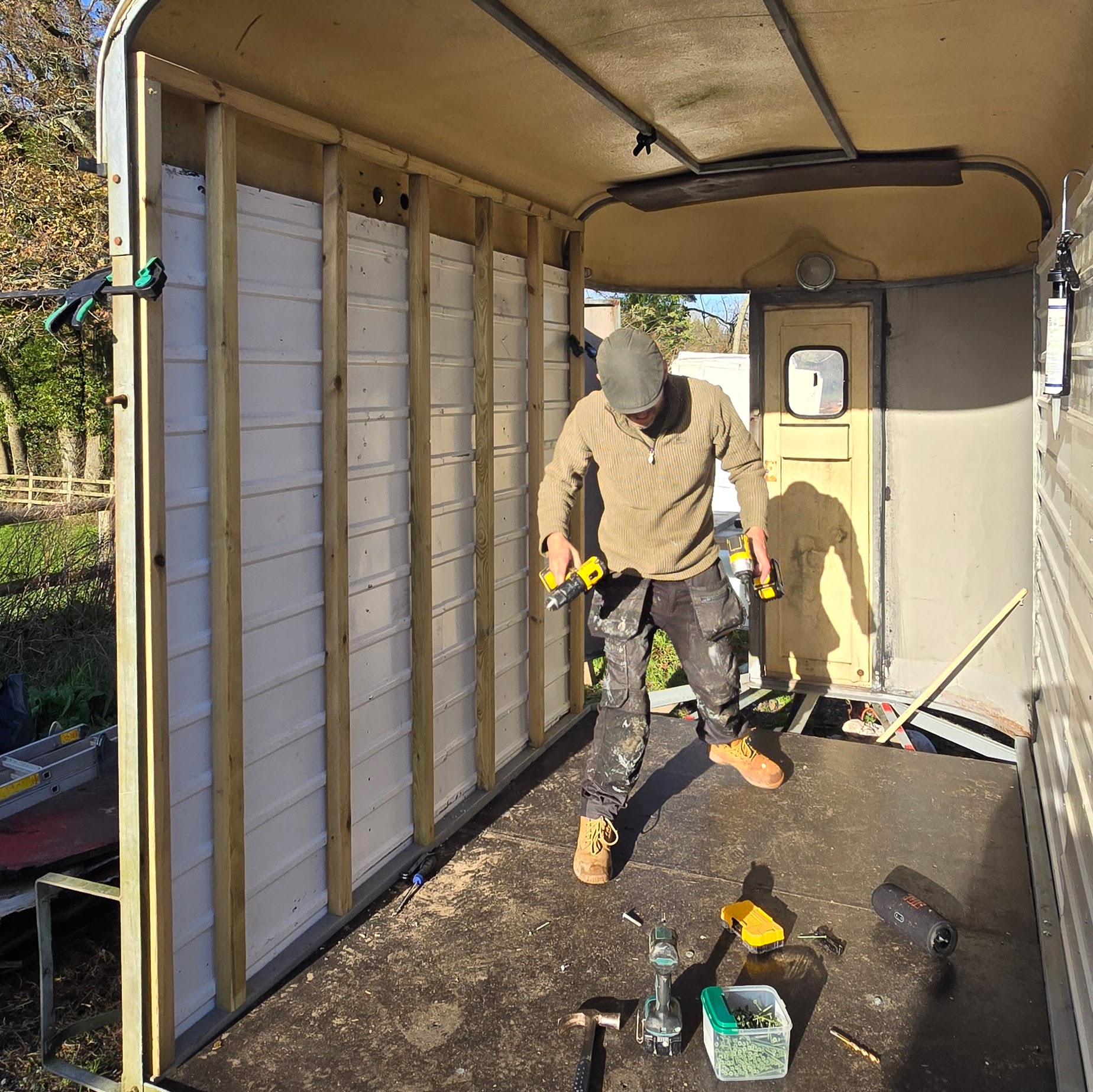 Adam inside the horsebox trailer during the build, drill in hand